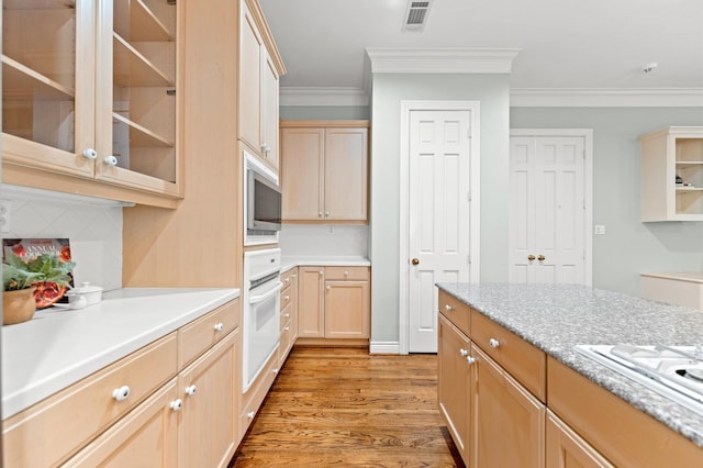 kitchen with light wood-type flooring, white appliances, visible vents, and light brown cabinetry