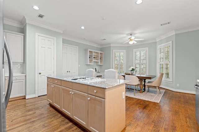 kitchen featuring crown molding, visible vents, wood finished floors, and a center island