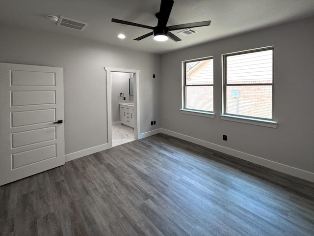 unfurnished bedroom featuring baseboards, connected bathroom, visible vents, and wood finished floors