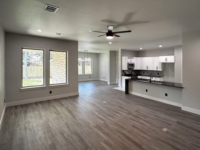 kitchen with visible vents, open floor plan, appliances with stainless steel finishes, tasteful backsplash, and dark countertops