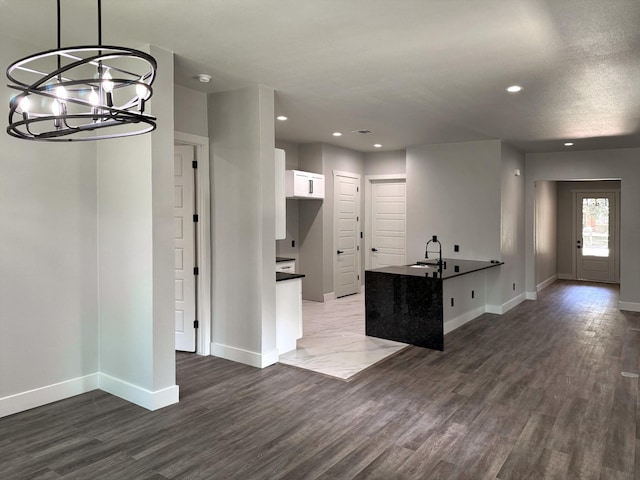 kitchen featuring dark countertops, recessed lighting, white cabinetry, wood finished floors, and baseboards