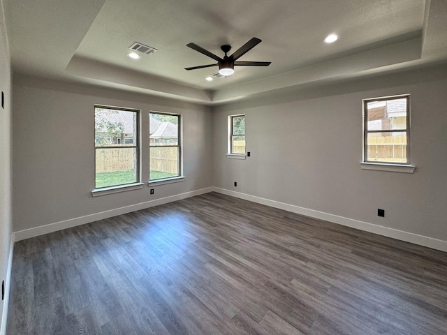 empty room featuring visible vents, a tray ceiling, and baseboards