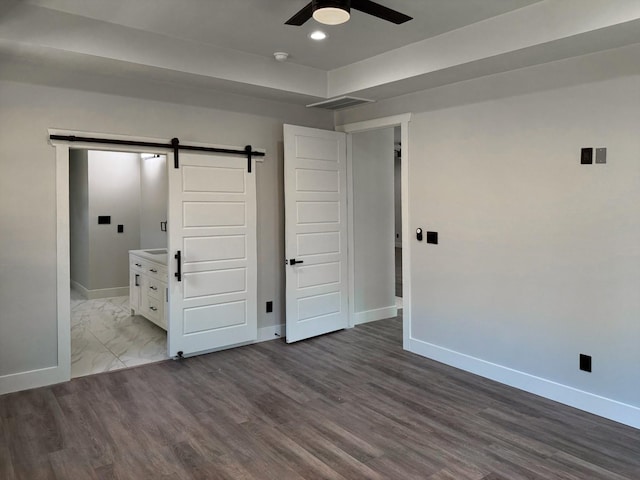 unfurnished bedroom featuring a barn door, visible vents, and baseboards