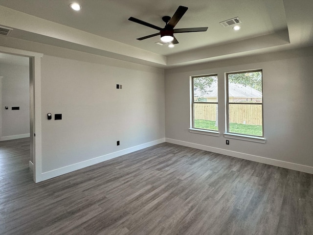 unfurnished room with a raised ceiling, dark wood finished floors, and baseboards