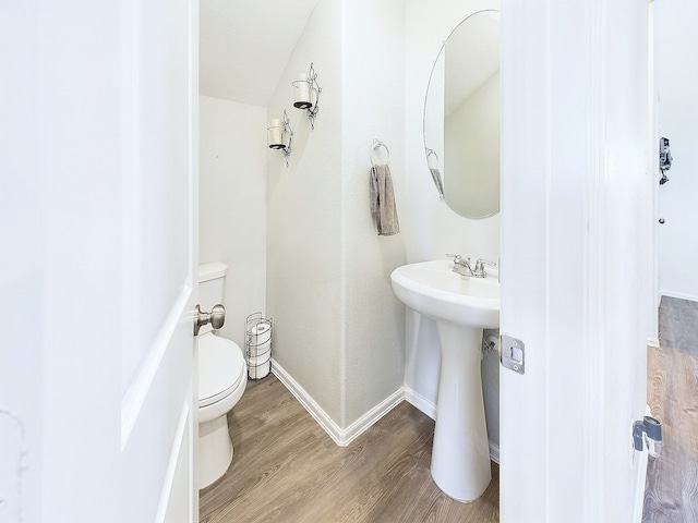 bathroom with toilet, a sink, baseboards, and wood finished floors