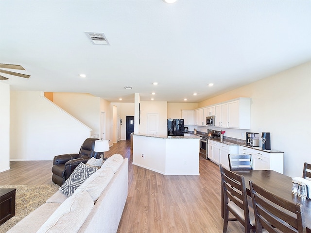 kitchen featuring light wood-style flooring, stainless steel appliances, visible vents, white cabinets, and open floor plan