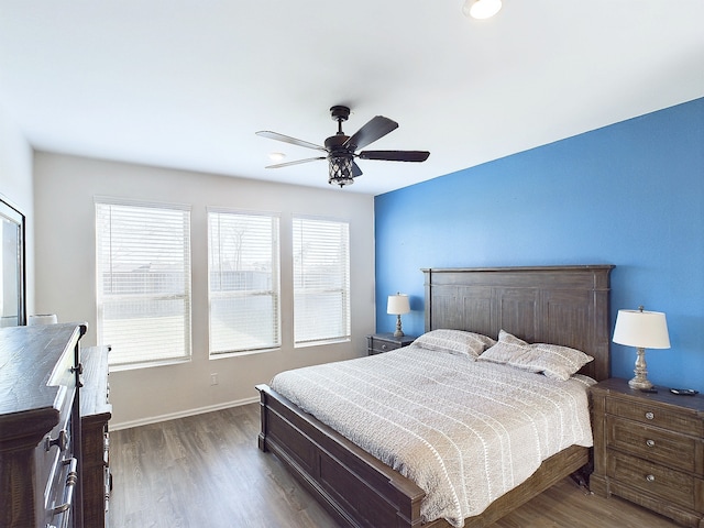 bedroom featuring a ceiling fan, baseboards, and wood finished floors