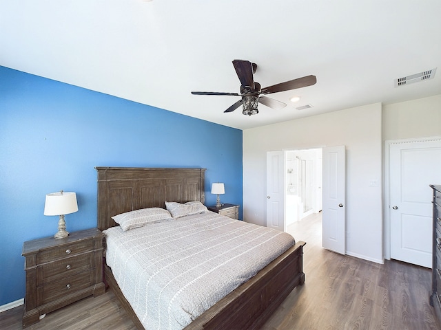 bedroom with wood finished floors, visible vents, and baseboards