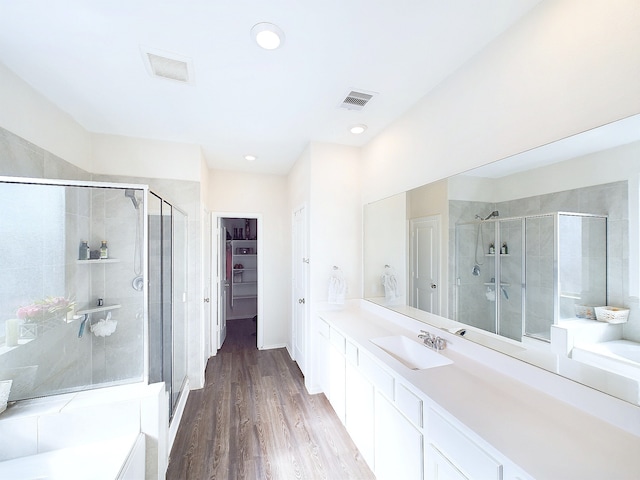 full bathroom with a shower stall, a bath, and wood finished floors