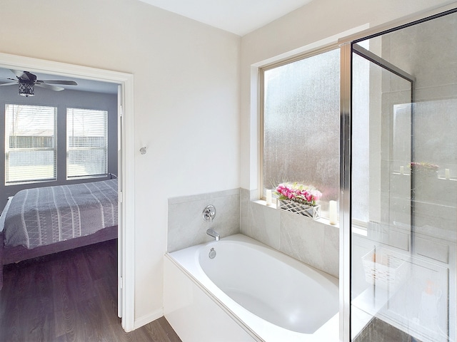 bathroom with ceiling fan, wood finished floors, a bath, a stall shower, and ensuite bath