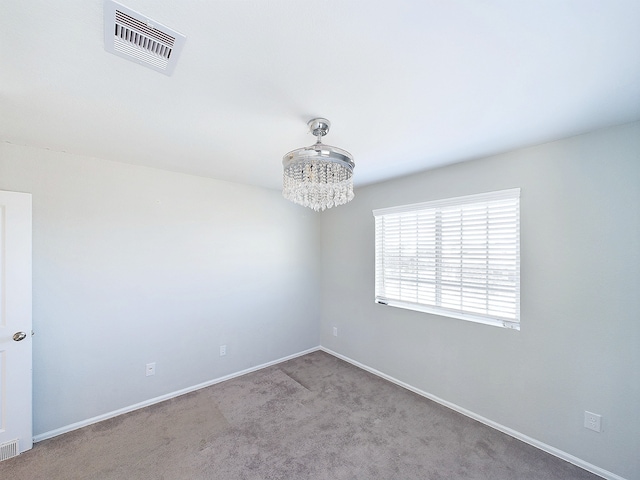 carpeted spare room featuring a chandelier, visible vents, and baseboards