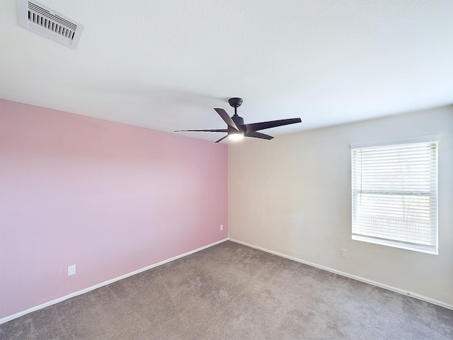 carpeted empty room with baseboards, visible vents, and a ceiling fan