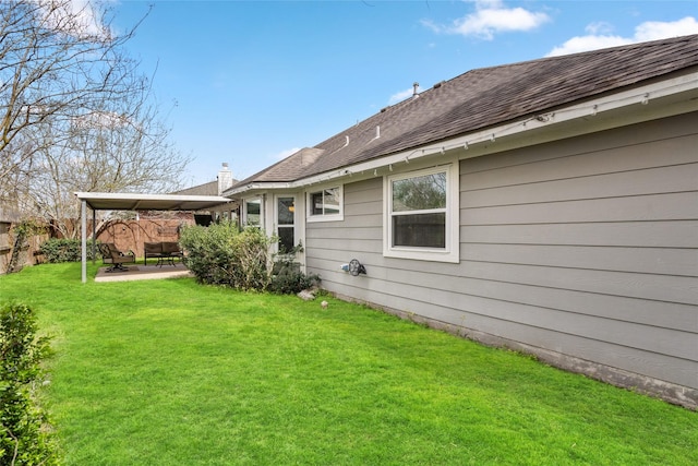 back of property featuring a yard, a shingled roof, a patio area, and fence