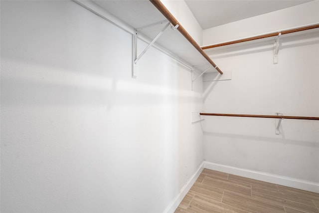 walk in closet with wood finish floors