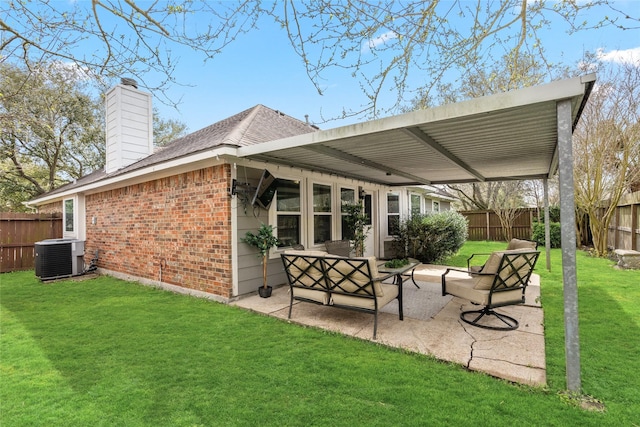 back of house featuring central AC unit, fence, a yard, a patio area, and brick siding