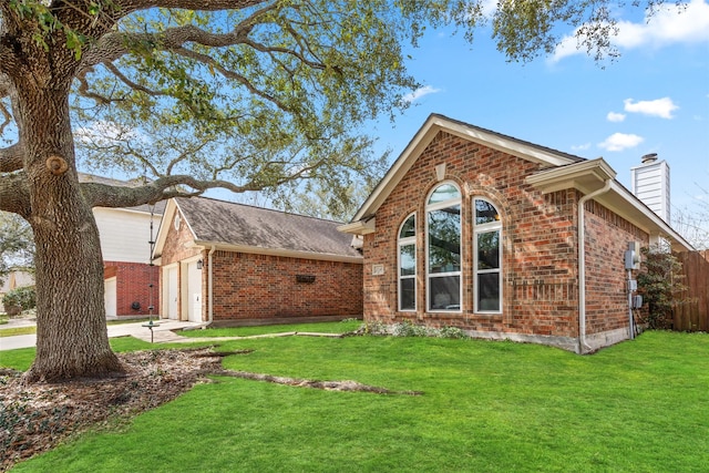 view of property exterior with a garage, brick siding, driveway, a lawn, and a chimney