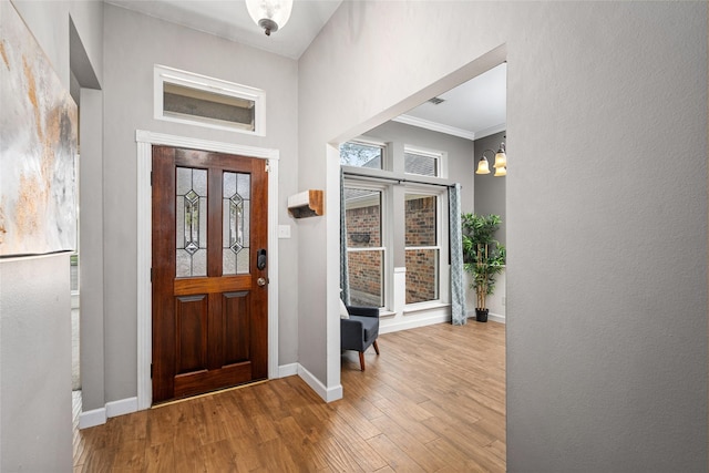 entryway featuring crown molding, wood finished floors, and baseboards