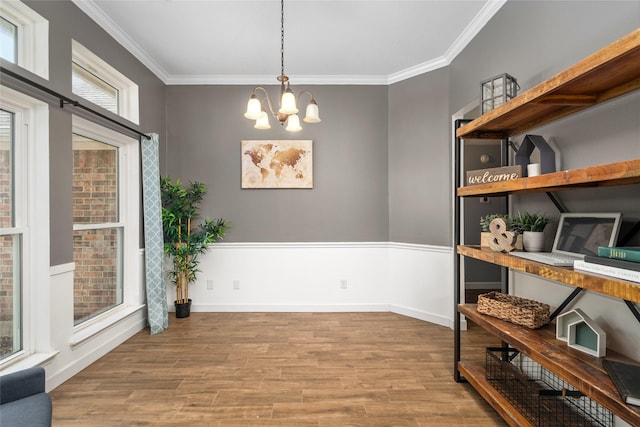 dining space featuring a chandelier, baseboards, wood finished floors, and crown molding