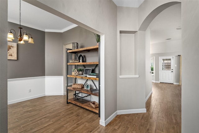 hall featuring arched walkways, baseboards, and wood finished floors