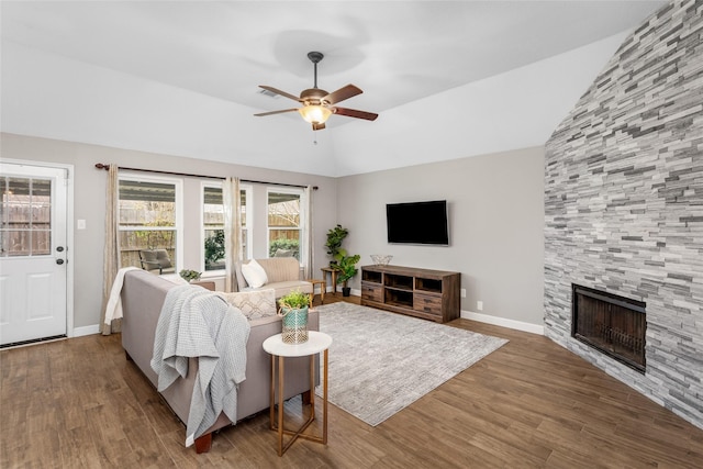 living room featuring lofted ceiling, a large fireplace, ceiling fan, and wood finished floors