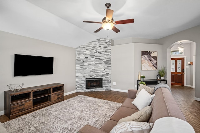 living area with arched walkways, lofted ceiling, a tiled fireplace, and wood finished floors