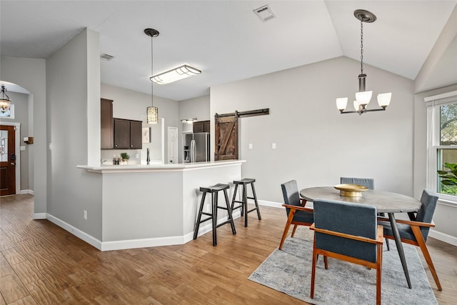 dining room featuring arched walkways, visible vents, a notable chandelier, and a barn door