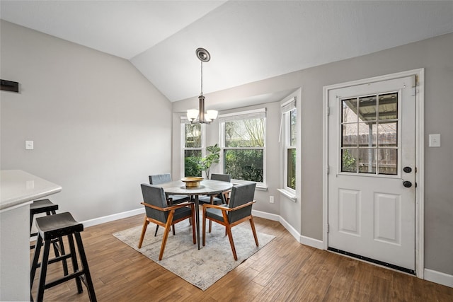 dining area featuring an inviting chandelier, baseboards, vaulted ceiling, and wood finished floors