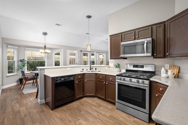 kitchen with stainless steel appliances, a peninsula, a sink, visible vents, and dark brown cabinets