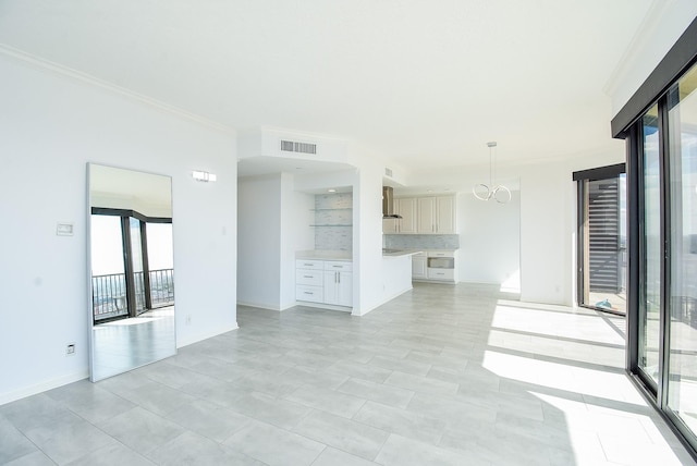 unfurnished living room with baseboards, a notable chandelier, visible vents, and crown molding