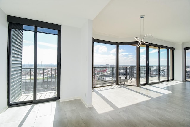 empty room with an inviting chandelier, baseboards, and a wealth of natural light