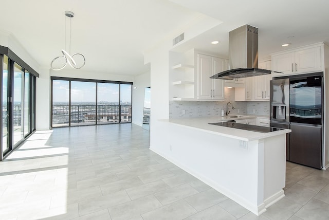 kitchen with visible vents, island exhaust hood, light countertops, stainless steel refrigerator with ice dispenser, and open shelves