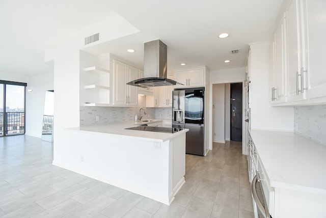 kitchen featuring visible vents, island range hood, a peninsula, refrigerator with ice dispenser, and open shelves