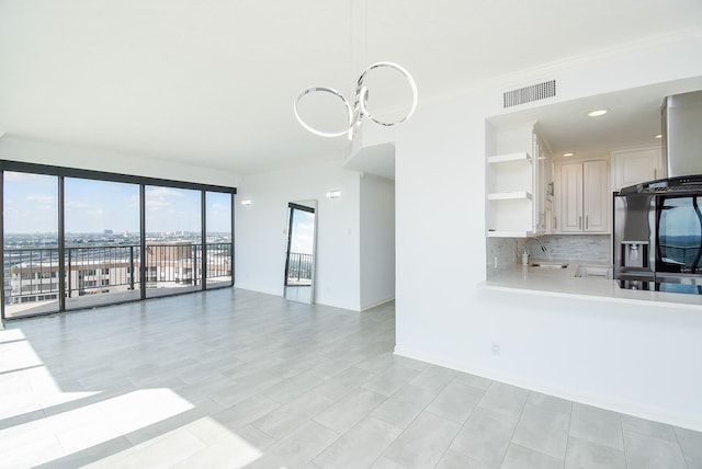 unfurnished living room with ornamental molding, visible vents, a sink, and a city view