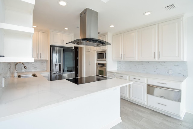 kitchen featuring visible vents, appliances with stainless steel finishes, island exhaust hood, a sink, and a warming drawer