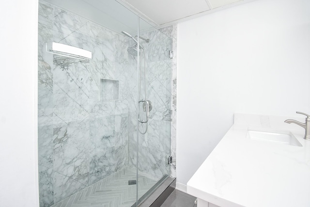 bathroom featuring a marble finish shower and a sink