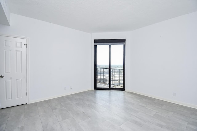 spare room featuring baseboards and a textured ceiling