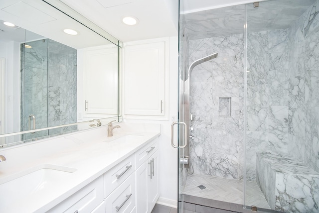 full bathroom with recessed lighting, a sink, a marble finish shower, and double vanity