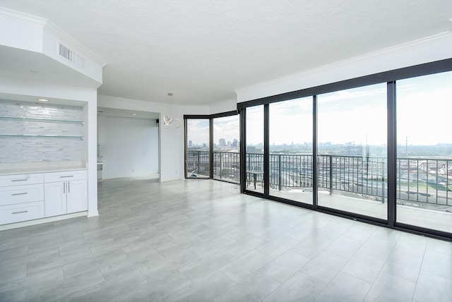 unfurnished room with ornamental molding, a view of city, visible vents, and a textured ceiling