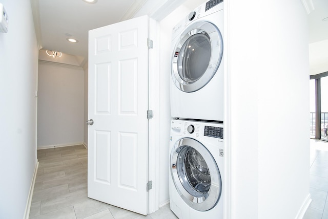 clothes washing area featuring laundry area, baseboards, stacked washer / dryer, and recessed lighting