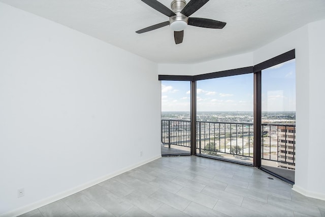 empty room featuring a ceiling fan, a view of city, a textured ceiling, and baseboards