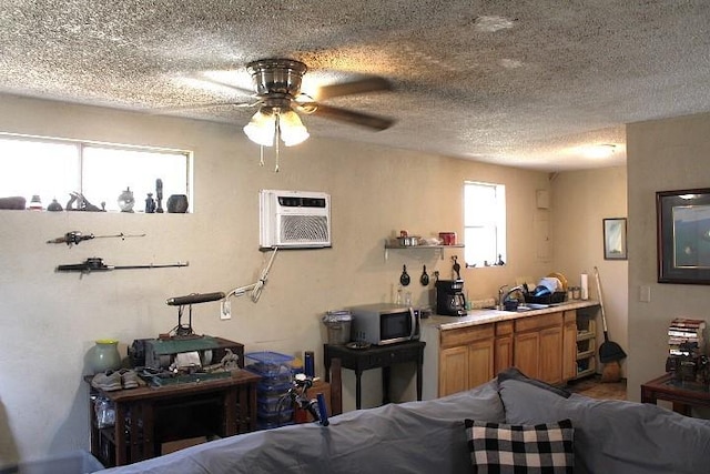 interior space with a textured ceiling, a sink, a wall mounted AC, brown cabinets, and stainless steel microwave