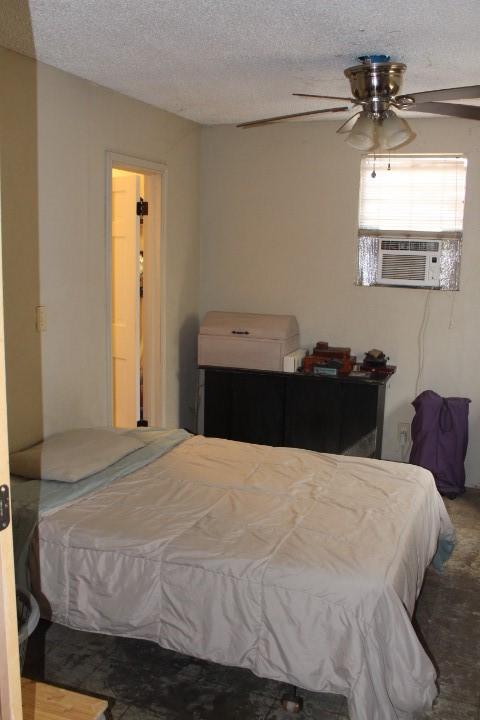 bedroom featuring carpet floors, cooling unit, ceiling fan, and a textured ceiling