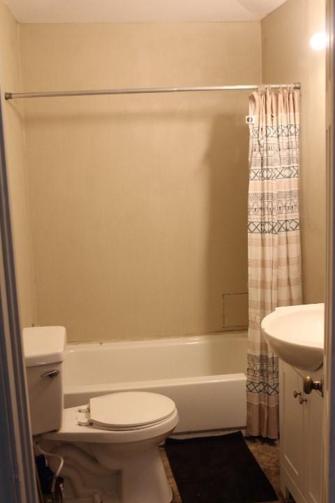 bathroom featuring toilet, shower / tub combo, and a sink