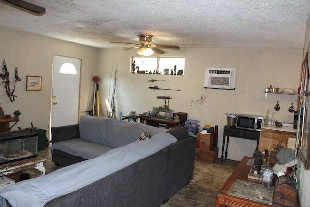 living room featuring a ceiling fan, a wall unit AC, and a textured ceiling