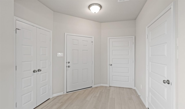 foyer featuring light wood-type flooring, baseboards, and visible vents