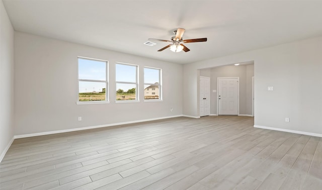 empty room featuring light wood-style flooring, visible vents, ceiling fan, and baseboards