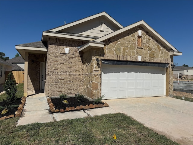 view of front of home with an attached garage, concrete driveway, stone siding, and brick siding