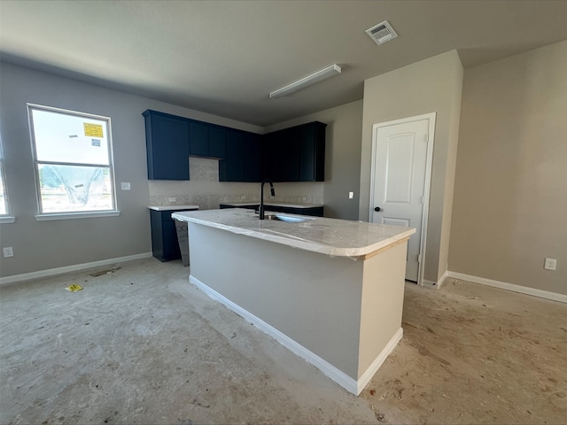 kitchen with a sink, visible vents, baseboards, and an island with sink