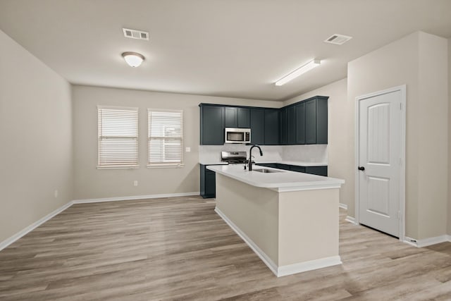 18798 Lucas Michael Way, New Caney, TX 77357 - kitchen with appliances with stainless steel finishes, a sink, light countertops, light wood-type flooring, and a kitchen island with sink