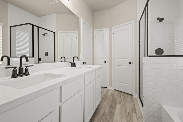 18798 Lucas Michael Way, New Caney, TX 77357 - bathroom featuring a shower stall, wood finished floors, double vanity, and a tub to relax in